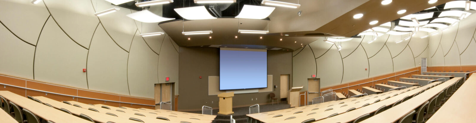 Empty lecture hall with podium and screen at the front of the room