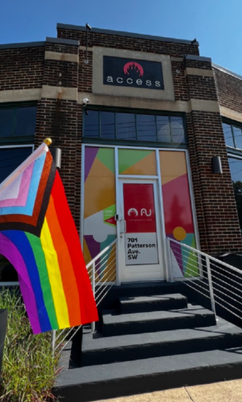 The front entrance of AccessU with a rainbow colored flag beside it.