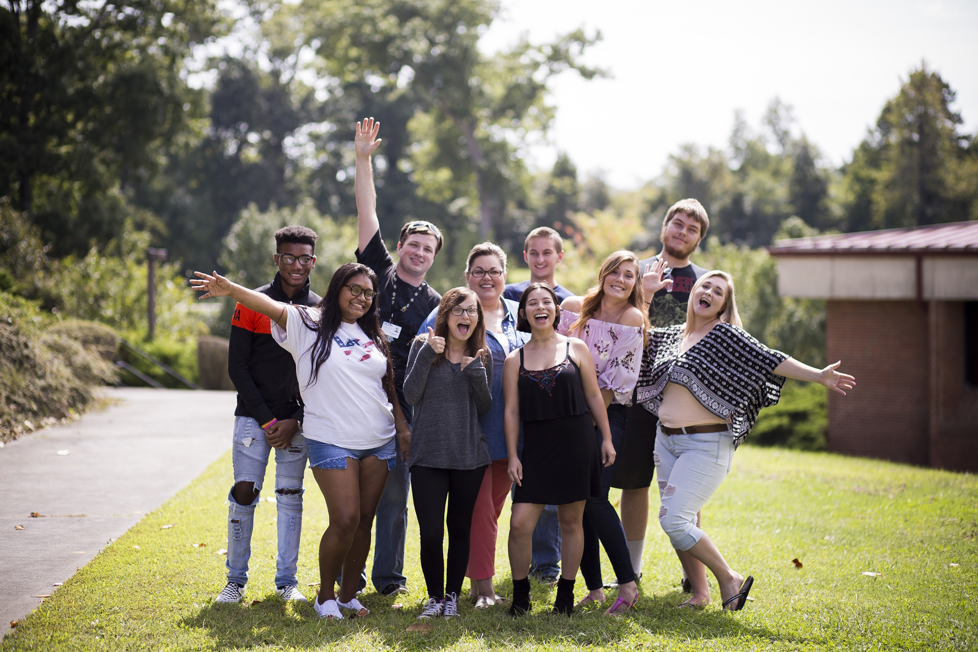 A group of students smiling and waving at the camera.