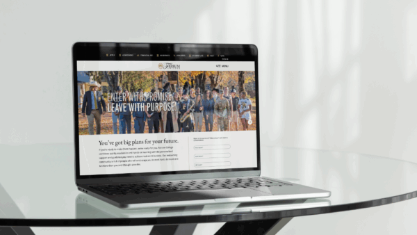 A laptop on a glass table displaying the Ferrum website.