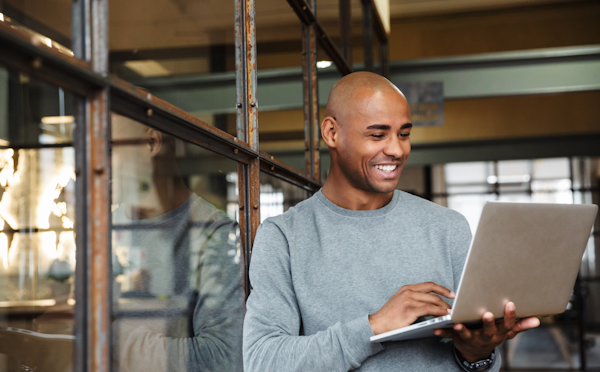 A man using a laptop while standing up.