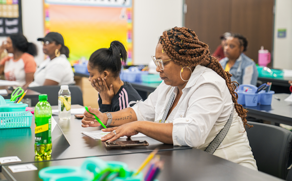 Women seated at rows of tables in a classroom