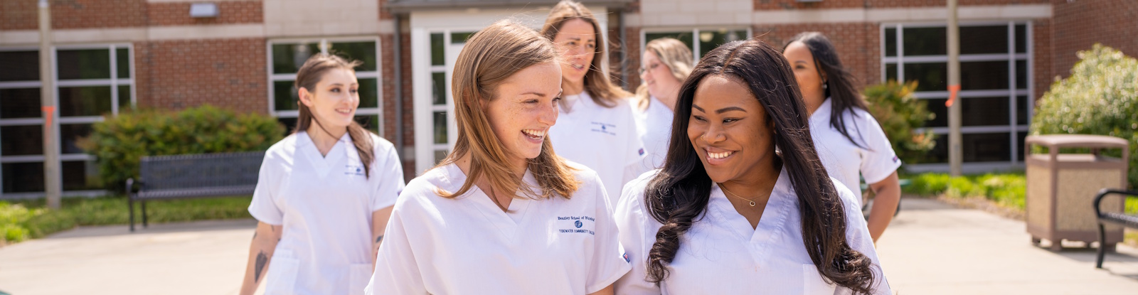 A group of nursing students walking out of a college building